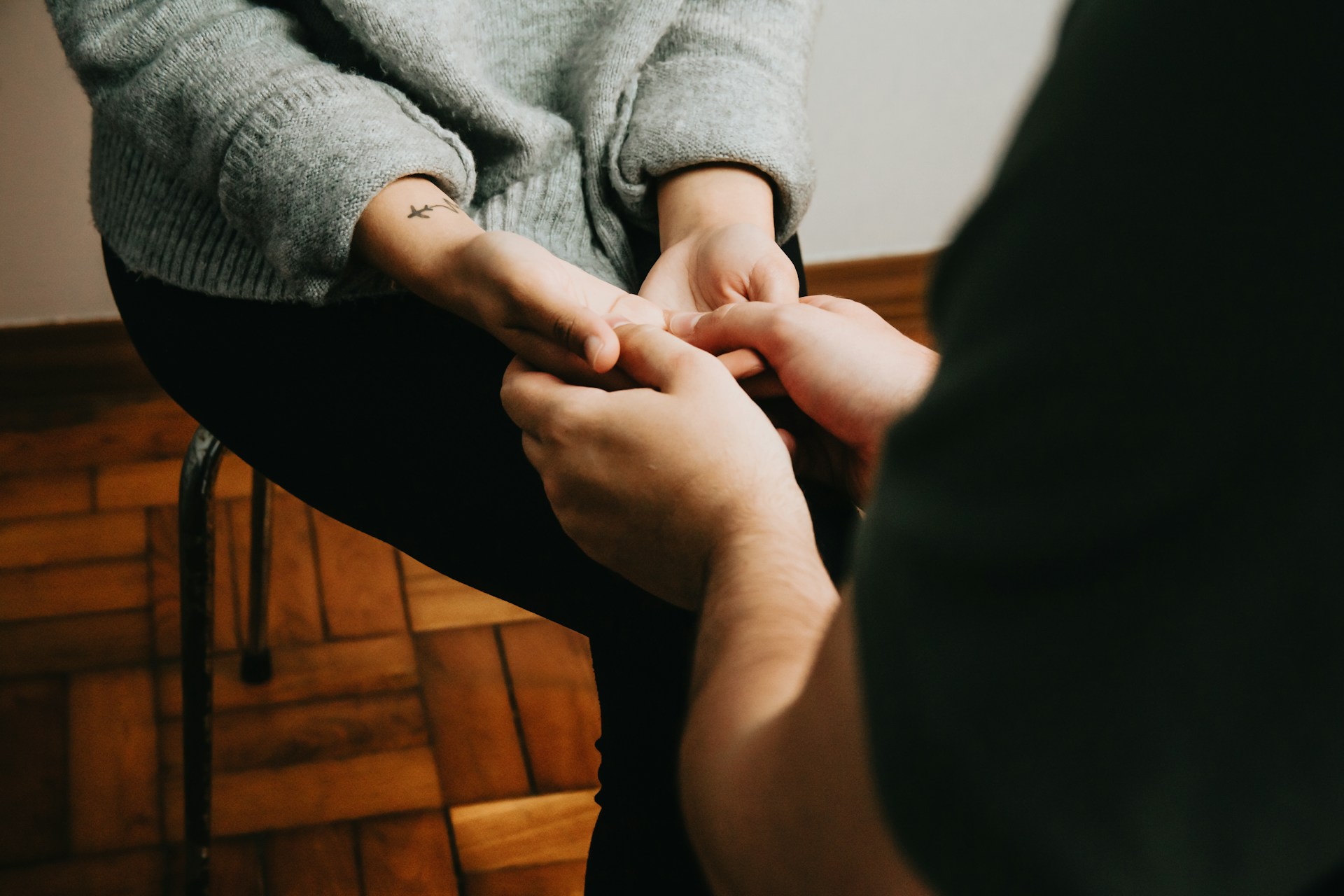Hands clasped together during a therapy session, no faces shown, symbolizing support in holistic psychiatric care.
