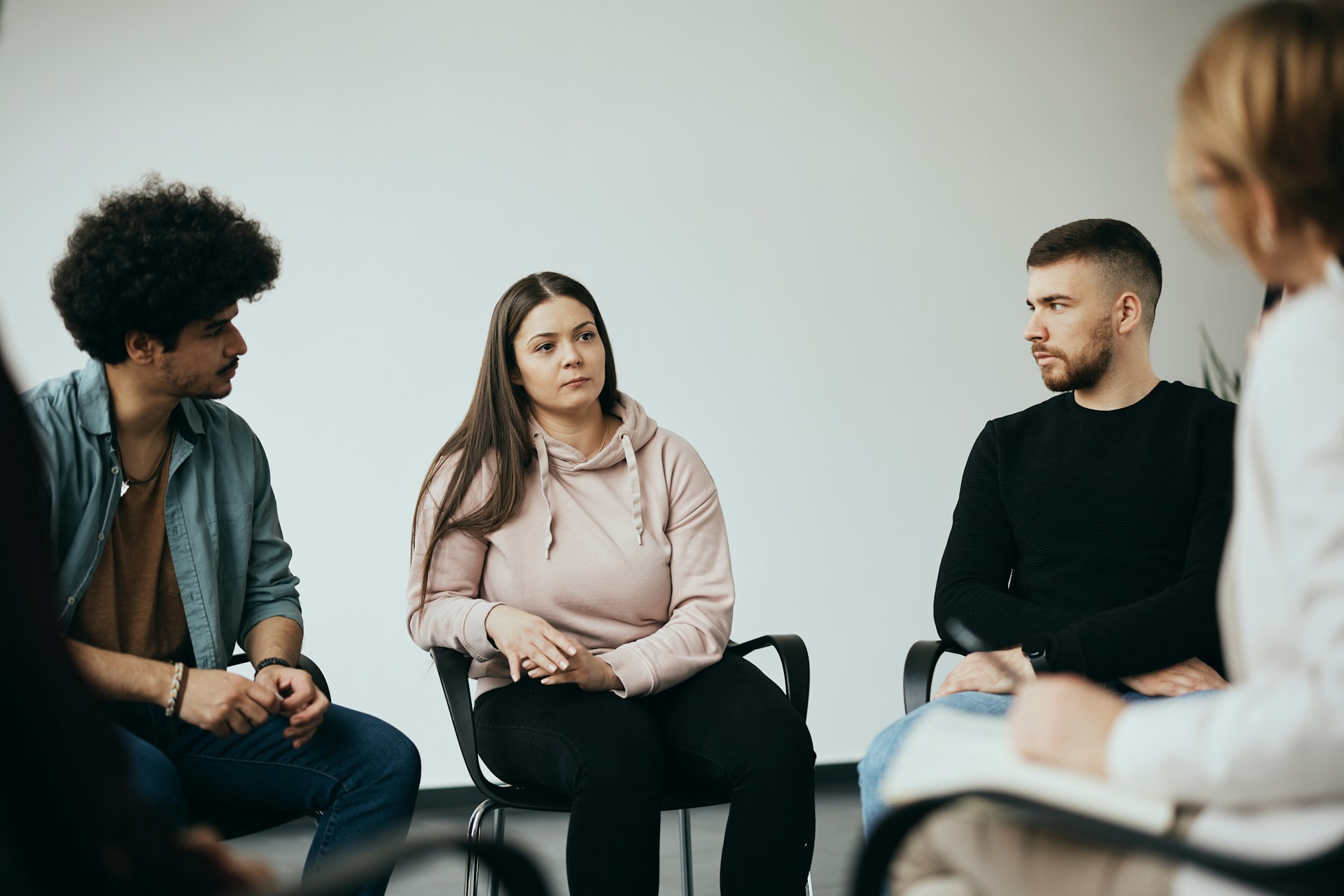 A small group of individuals sitting in a circle during a therapy session, sharing and supporting each other.