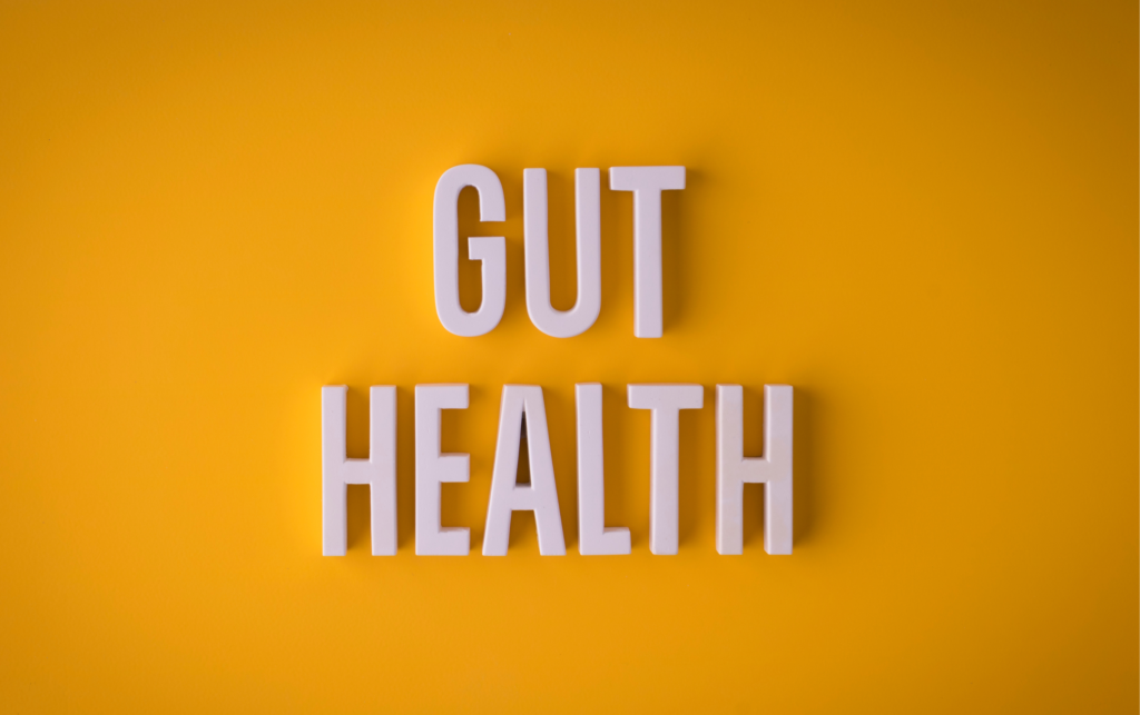 White 3D letters spelling “GUT HEALTH” on a bright yellow background, representing the connection between gut health and mental well-being.